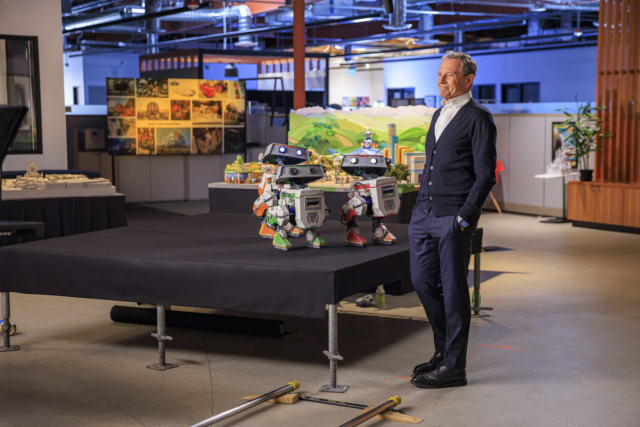 Disney-CEO-Defends-Park-Pricing-and-Plans-7-More-Cruise.jpg the ceo of walt disney company stands next to some new droids