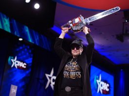 CEO of Tesla and SpaceX Elon Musk holding a chainsaw above his head.
