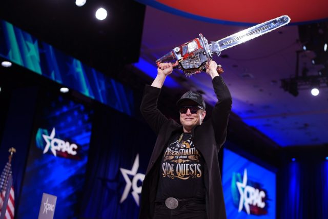 Elon-Musk-says-he-may-keep-doing-DOGE-work-for.jpg CEO of Tesla and SpaceX Elon Musk holding a chainsaw above his head.