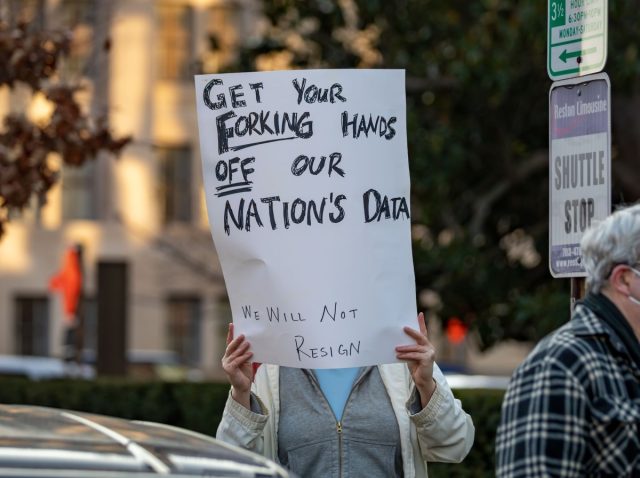 Federal-judge-allows-the-EFFs-lawsuit-against-DOGE-and-Elon.jpg a photo of a protesters in Washington DC with a sign that says "GET YOUR FORKING HANDS OFF OUR NATION'S DATA"