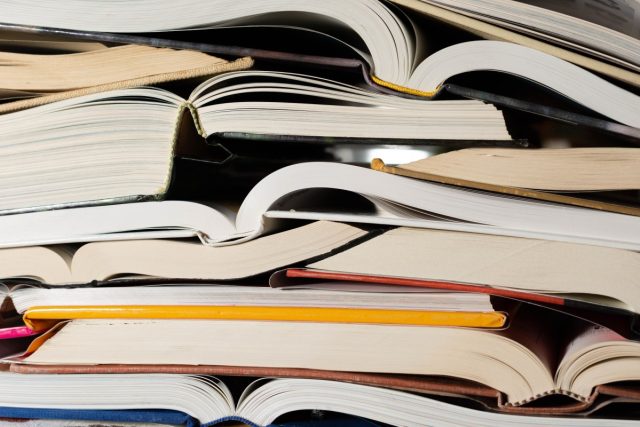 NaNoWriMo-shut-down-after-AI-content-moderation-scandals.jpg Stack of open books