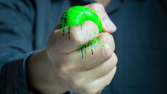 Not-just-Switch-2-ESA-warns-Trumps-tariffs-will-hurt.jpg A fist squeezing electronics until they ooze out between its fingers