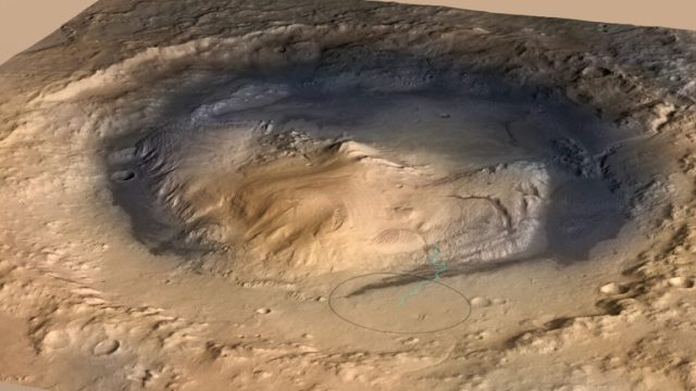 Rover-finds-hints-of-an-ancient-Martian-carbon-cycle.jpeg Image of a red-tinged landscape with a crater featuring a rounded peak.