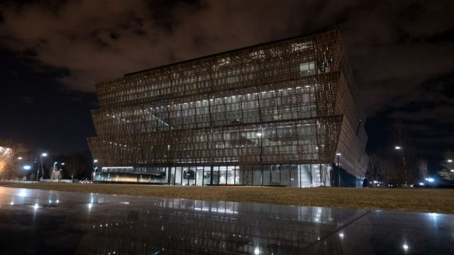 Smithsonian-Director-Says-Museum-Will-Be-Non-Partisan-in-Staff-Memo.jpg A night time view of a museum exterior.