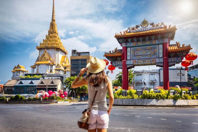 A woman looking at a temple and a gate in Thailand