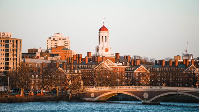 Trump-Administration-puts-22-billion-of-Harvards-research-money-on.jpg Image of older brick buildings with a river and bridge in the foreground.