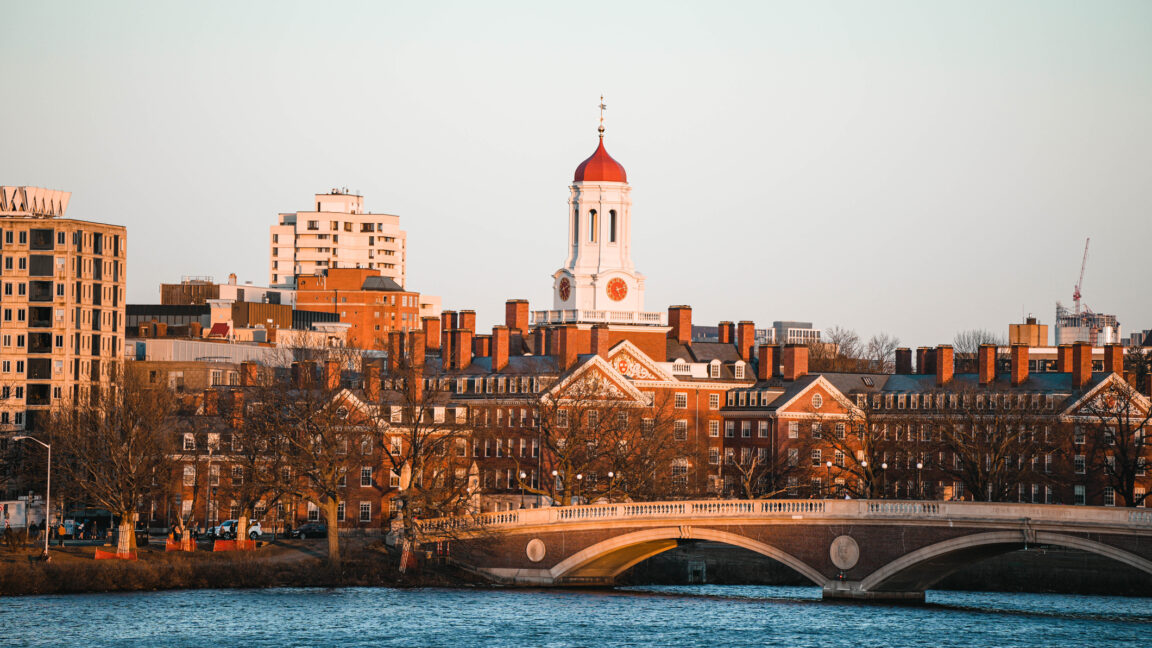 Trump-Administration-puts-22-billion-of-Harvards-research-money-on.jpg Image of older brick buildings with a river and bridge in the foreground.