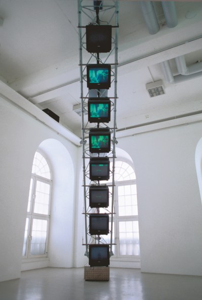A tower of TV screens suspended in a gallery.