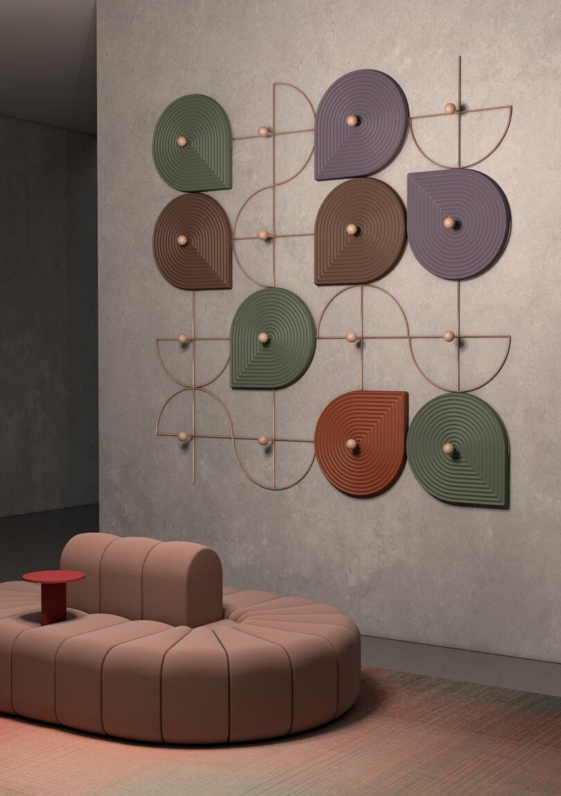 Sculptural wall art with geometric patterns and earth tones above a curved, beige sofa 