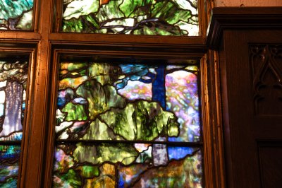 Detail of a stained glass window showing trees with various confetti glass techniques. 