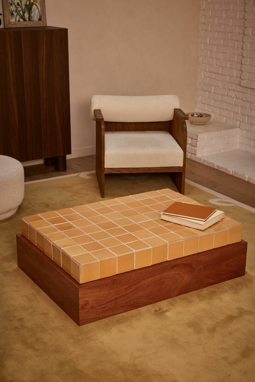 A wooden coffee table with a tiled surface, two closed books on top—one titled 