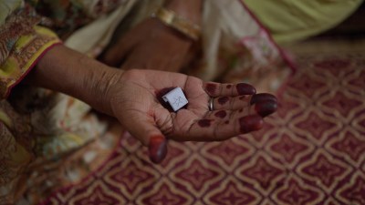 An inked hand holding out a tile.