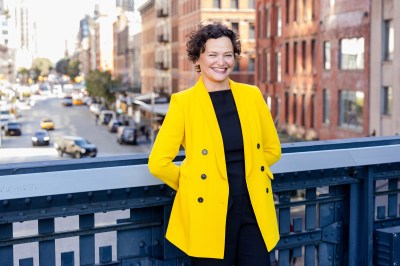 Portrait of Cecilia Alemani, standing on a section of the High Line that crosses over a Manhattan street below.