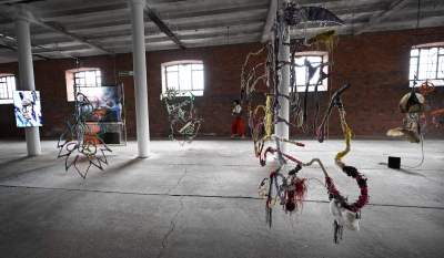 A group of hanging sculptures in a raw space.