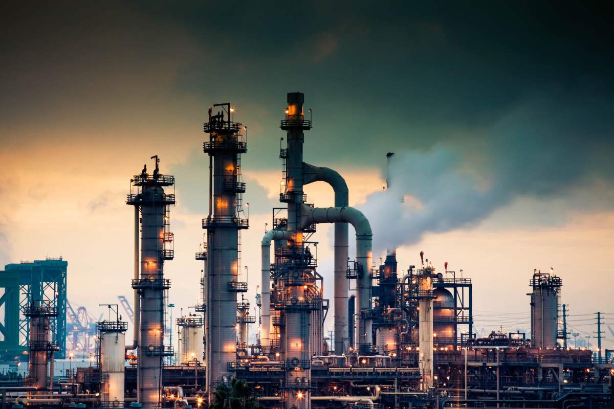 Ara-Partners-new-800M-fund-will-decarbonize-old-industrial-assets.jpeg A steaming, glowing mass of smoke stacks and distillation towers connected by conduit and pipe racks towers in the early morning light in front of the Port of Los Angeles.