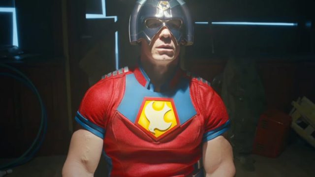 The-Justice-League-is-not-impressed-in-Peacemaker-S2-teaser.jpg well muscled mad in Peacemaker outfit sitting down, with a silver helmet on his head