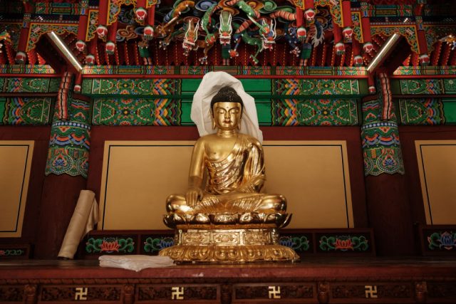 A golden statue of a lady with her legs crossed.