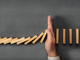 Chain Reaction In Business Concept, Businessman Intervening Dominoes Toppling; cut spending