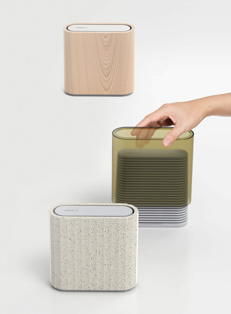 Three rectangular, modern storage containers in vibrant finishes are shown; a hand lifts the translucent green container. The other two feature beige wood grain and speckled stone designs.
