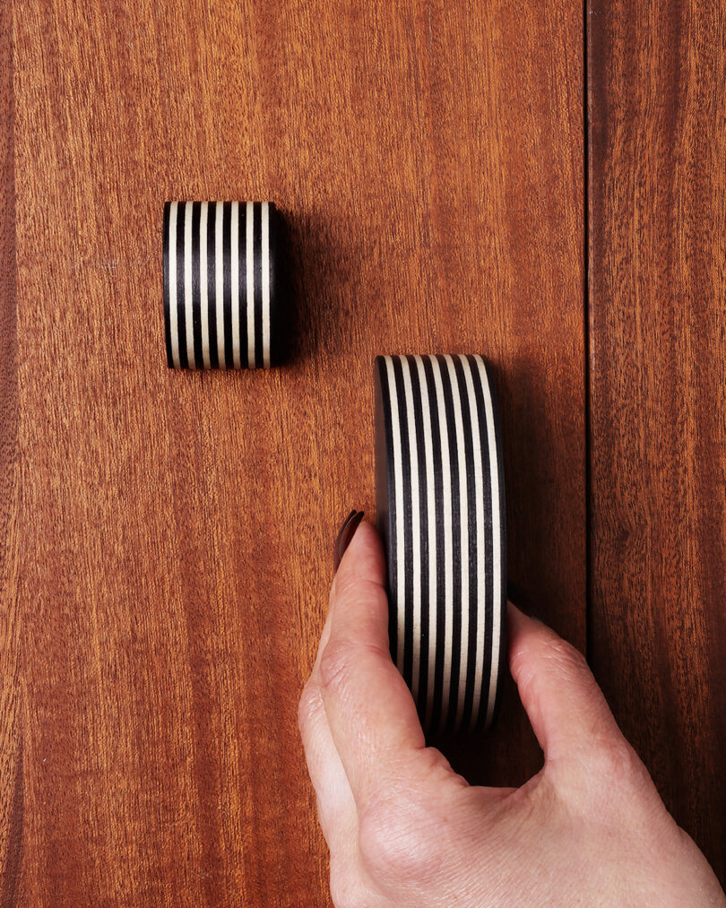 A hand holds a black-and-white handle next to a pull