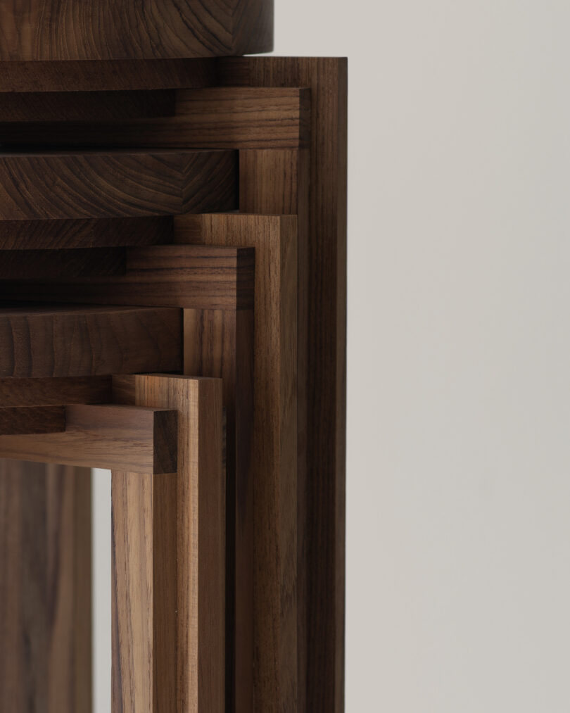 Stacked wooden frames of varying sizes arranged in an overlapping pattern against a plain background. The frames are made of wood with visible grain patterns
