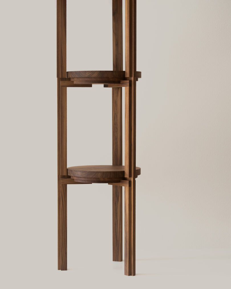 A minimalist wooden shelving unit with a light wood finish, featuring asymmetrical design and narrow vertical lines against a plain background