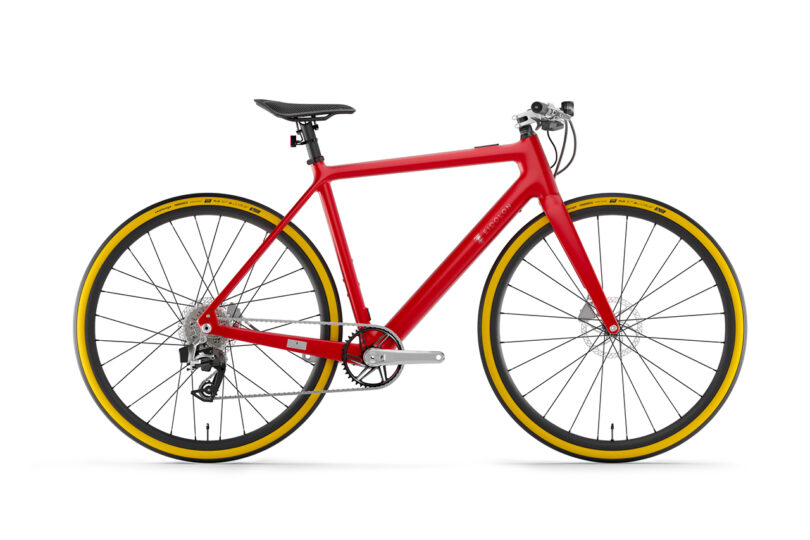Red bicycle with a sleek frame, yellow-accented tires, and a minimalist design, shown from the side against a plain white background.