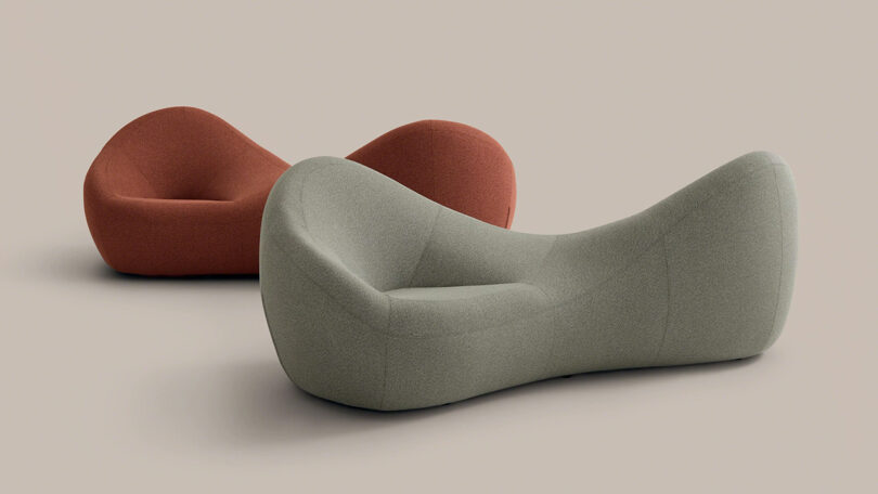 Two modern, sculptural lounge chairs in muted green and rust colors are placed on a plain, light background.