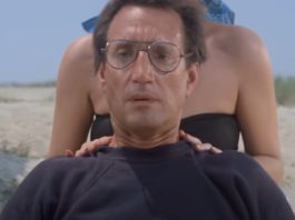 closeup of man in glasses on the beach looking out to the water with growing horror