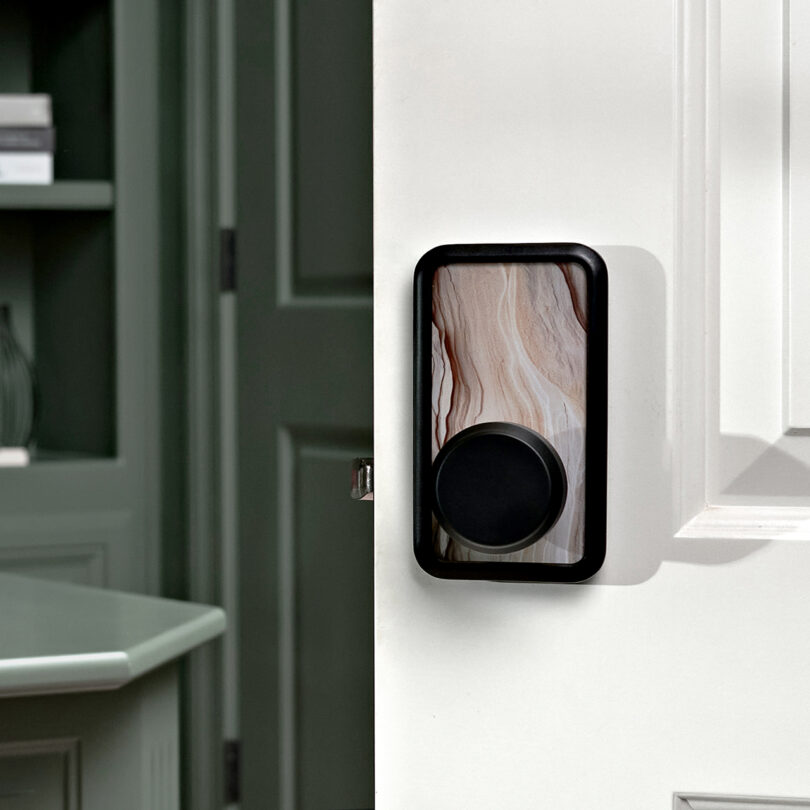 A rose quartz smart door lock is installed on a white door, partially open to reveal a blurred bedroom interior.