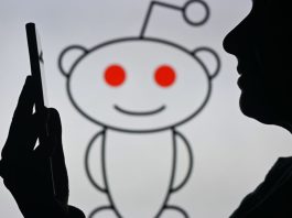 An image of a woman holding a cell phone in front of the Reddit logo displayed on a computer screen, on April 29, 2024, in Edmonton, Canada.