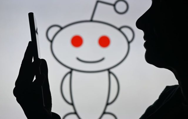Reddit-CEO-pledges-site-will-remain-written-by-humans-and.jpg An image of a woman holding a cell phone in front of the Reddit logo displayed on a computer screen, on April 29, 2024, in Edmonton, Canada.