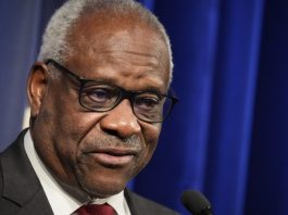 Supreme Court Justice Clarence Thomas speaking into a microphone at an event.