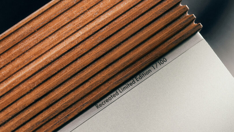 Close-up view of the corner of a book with a wooden-textured spine, reminiscent of the Beosystem 3000c design, and a page labeled 