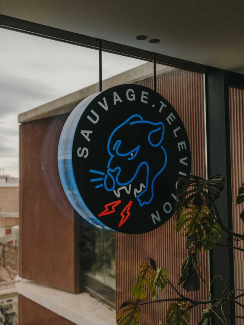 A round neon sign with a blue outline of a growling panther, red lightning bolts, and the words 