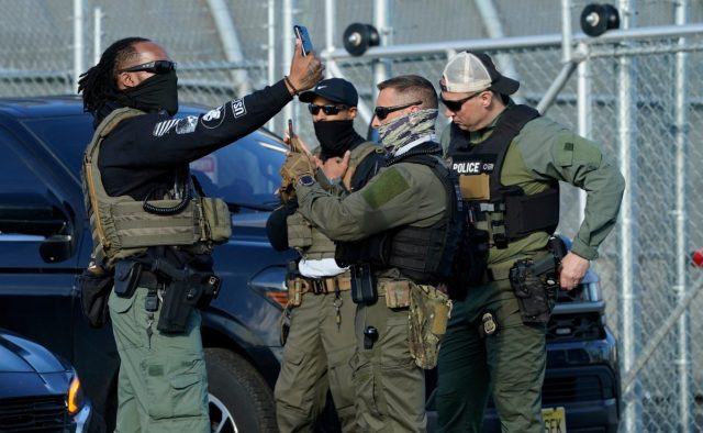Can-an-‘ethical-spyware-maker-justify-providing-its-tech-to.jpg Immigration and Customs Enforcement (ICE) agents use their phones near protestors at a demonstration in Elizabeth, New Jersey May 7, 2025, outside Delaney Hall, a newly converted immigrant detention centre.
