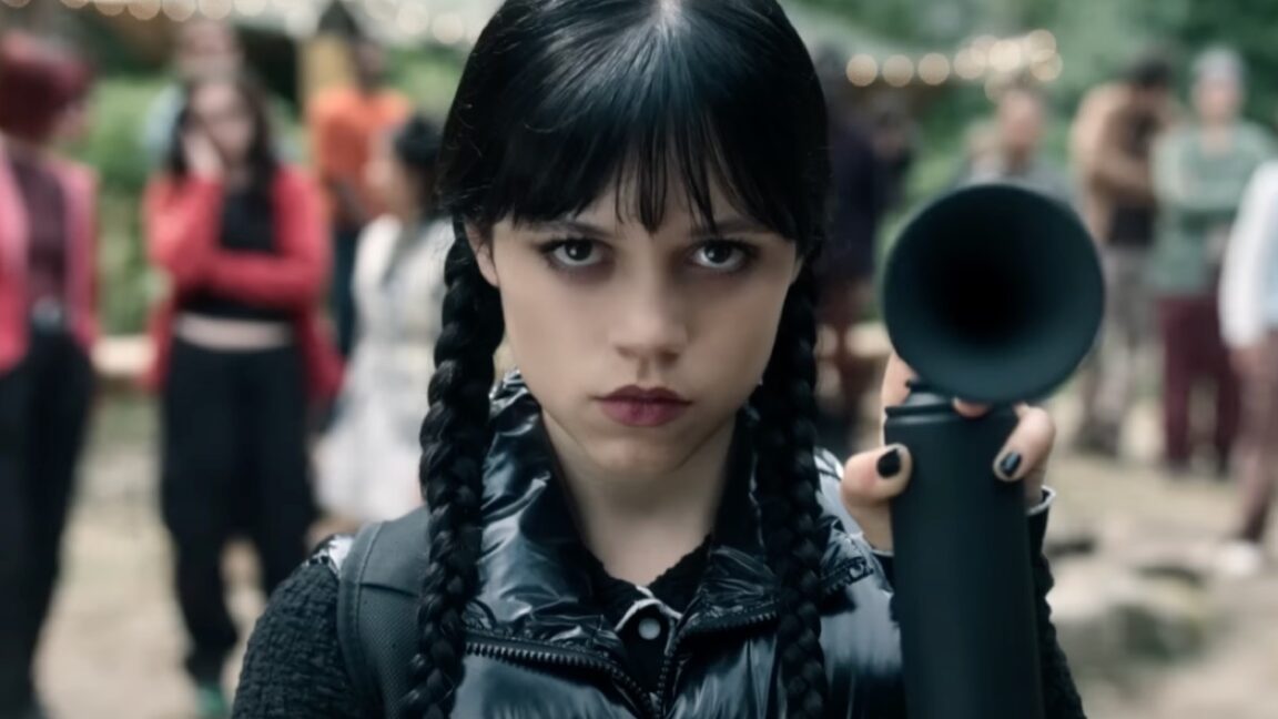 dark haired goth girl in pig tails dressed all in black holding up an emergency horn