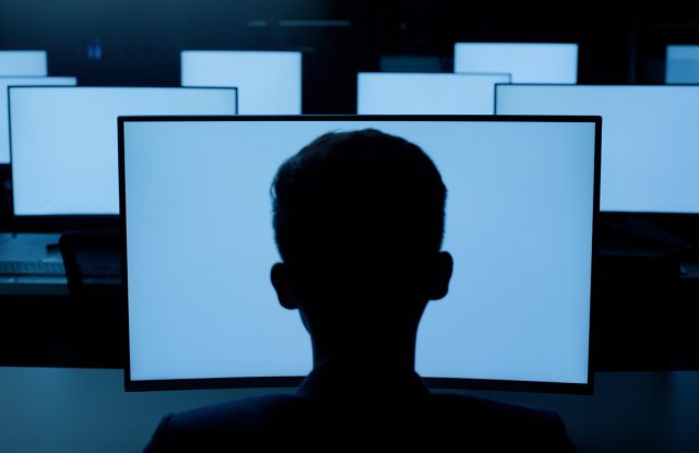 Everyone-in-tech-has-an-opinion-about-Soham-Parekh.jpg Person, desktop or blue screen at night in information technology lab with back of developer or programmer. Software development, networking and system administration for computer or connection