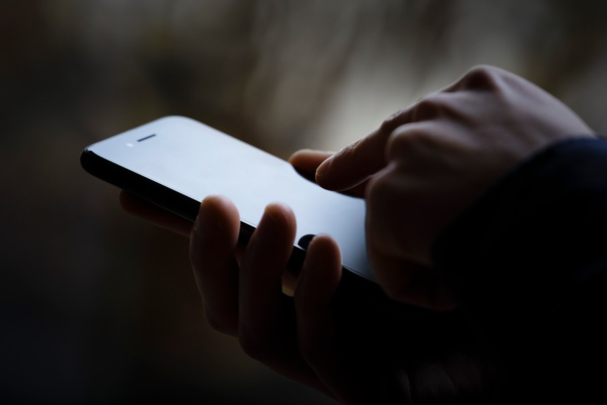 Hackers-are-trying-to-steal-passwords-and-sensitive-data-from.jpg A photo of a person's phone in someone's hand, the image is darkened.