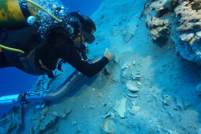 Hundreds-of-Ancient-Ceramics-Found-In-Preserved-Shipwreck-in-Turkey.jpg A diver carefully brushes sand away from stacked ceramics found in a shipwreck off the coast of Turkey.