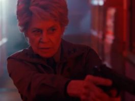 older woman with short gray hair looking grim while pointing a revolver