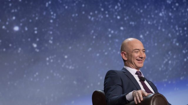 Jeff Bezos at a space conference, sitting in front of a picture of the stars in the night sky.